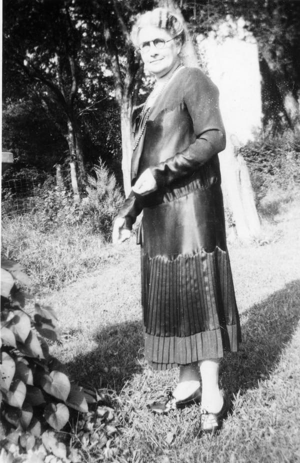 A black and white photo of Febb Burn standing in a garden.