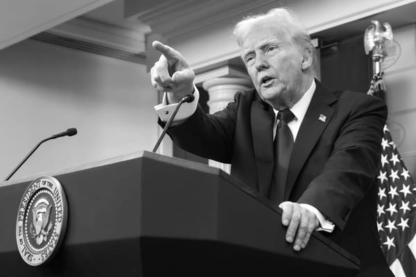 Black and white image: Trump behind a podium, pointing at someone.